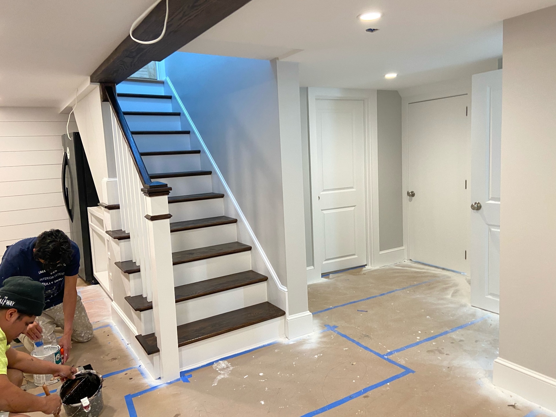Freshly painted basement interior with dark wood staircase and white trim by Lima Painting in Greater Boston MA