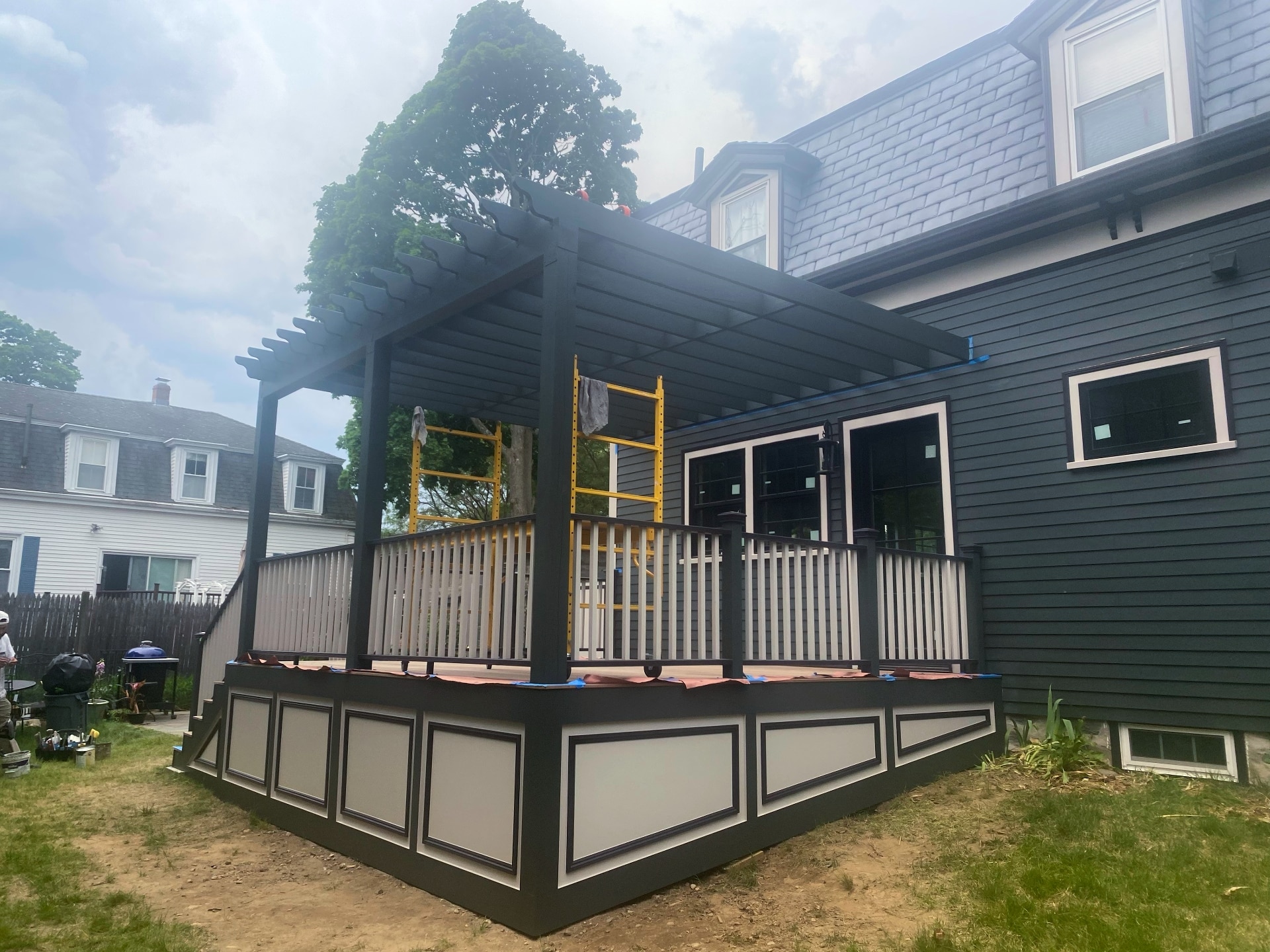 Painted deck and pergola with charcoal and white trim alongside freshly painted home exterior by Lima Painting in Greater Boston MA