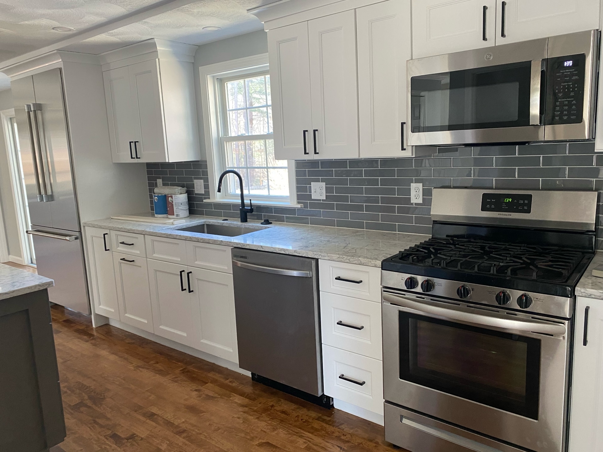 Freshly painted white kitchen cabinets with gray subway tile backsplash by Lima Painting in Greater Boston MA