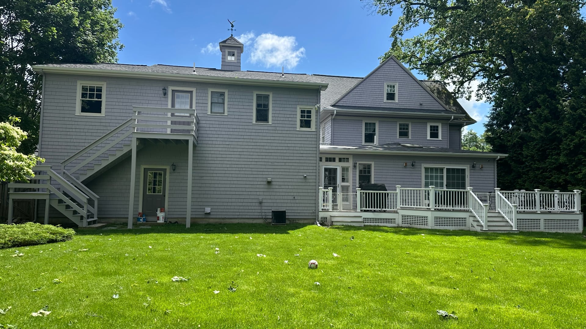 Rear exterior of large Victorian home painted in lavender gray with white deck and trim by Lima Painting in Greater Boston MA